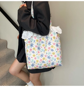 Close-up of floral canvas tote bag with delicate lace trim detail shown on a model