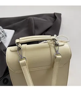 Détail du sac à main en cuir beige avec chaîne en perles et finitions métalliques