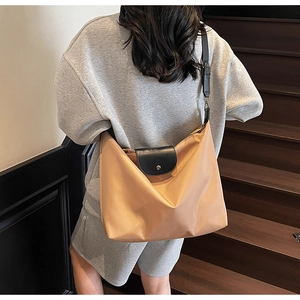 Detail of apricot oxford tote bag featuring black leather strap and silver metal buckle