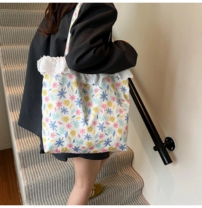 Detail shot of canvas tote bag featuring floral print and white lace trim decoration