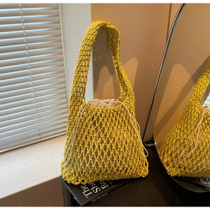 Detail of yellow woven bucket bag with hollow mesh design and drawstring fabric liner