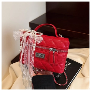 Détail du sac boîte rouge matelassé avec perles de nacre et nœud en dentelle