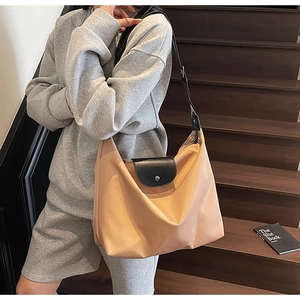 Close-up of khaki Oxford tote bag with black leather flap on wooden stairs