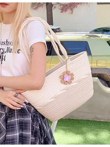 Sac cabas bicolore en paille tressée avec breloque fleur porté par un mannequin