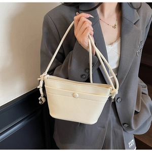 Vue détaillée du sac bandoulière en cuir blanc cassé avec poignée à nœud sur un modèle