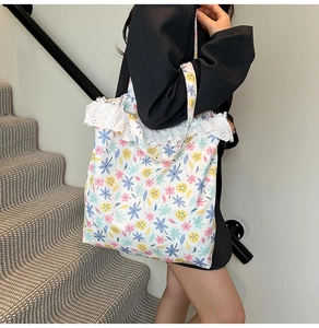 Detail of floral canvas tote bag with white lace trim shown on shoulder in daily use