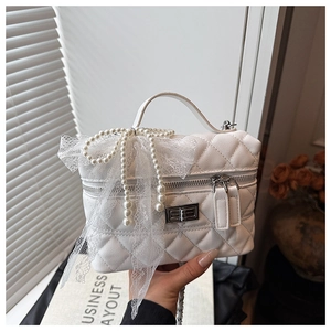 Détail du sac boîte matelassé blanc avec perles et un nœud en dentelle délicate