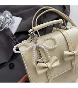 Gros plan du sac à dos en cuir blanc crème avec nœud et pendentif en perles