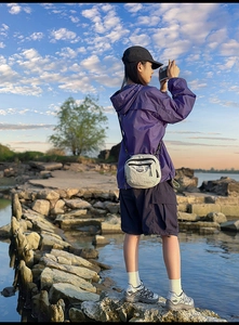 Dettaglio di una borsa a tracolla in nylon leggera con giacca viola durante l'outdoor
