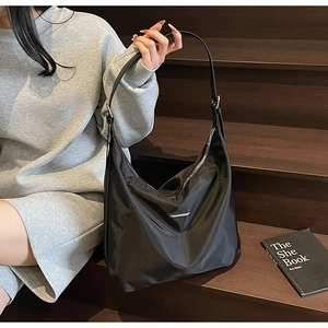 Close-up of black nylon hobo bag featuring silver metal trim and adjustable strap detail
