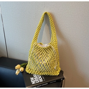 Detail of yellow woven bucket bag with white drawstring pouch and hollow mesh texture