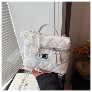 Détail du sac matelassé blanc avec nœud en dentelle et perles et fermoir argenté