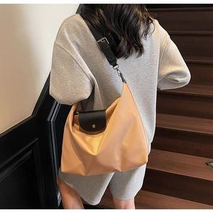 Detail of beige nylon tote bag with black leather flap and adjustable wide shoulder strap