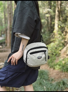 Vista dettagliata della borsa a tracolla bianca strutturata con cerniera e logo del brand