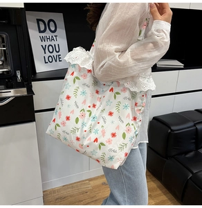 Close-up of white floral canvas tote bag featuring delicate lace trim and heart pattern