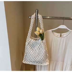 Detail of cream woven bucket bag showing intricate crochet mesh and drawstring inner pouch