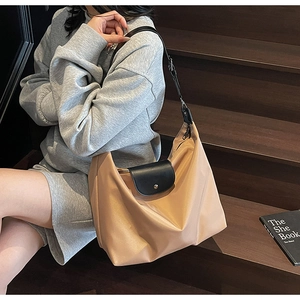 Detail of a large khaki oxford cloth tote bag worn by a model on wooden stairs