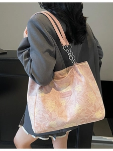 Pink floral canvas tote bag with chain strap shown from a side view on a model