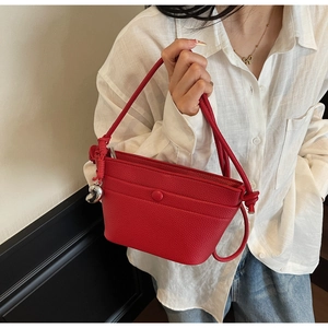 Détail du sac à main rouge en cuir avec poignée en corde tressée et pendentif coeur