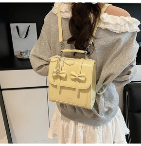 Vue détaillée d'un sac à dos jaune brillant avec nœuds décoratifs et chaîne de perles