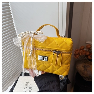 Détail du sac boîte jaune matelassé avec chaîne en perles et nœud en dentelle en PU