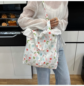 Detailed view of canvas tote bag featuring floral print and delicate white lace edges