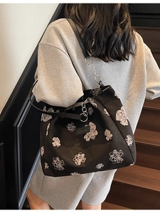 Floral print tote bag with black strap and silver chain detail on wooden staircase