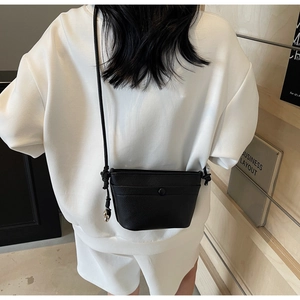 Détail d'un sac bandoulière en cuir noir avec ornement sphérique en métal argenté