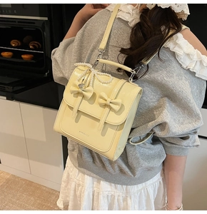 Sac à dos beige en similicuir verni avec nœuds et chaîne de perles porté par mannequin