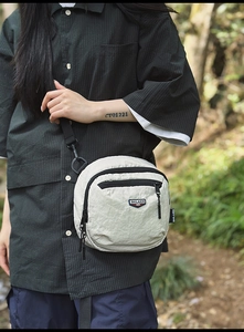 Dettaglio della borsa a tracolla in nylon grigio chiaro con tasche e cinturino