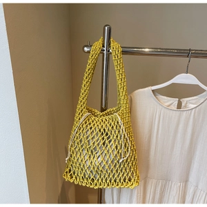 Detail of yellow mesh woven shoulder bag featuring coarse rope knots and a grey drawstring liner