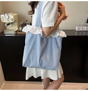 Close-up of blue and white striped canvas tote bag with delicate white lace trim details