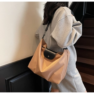 Close-up of khaki nylon tote bag with black leather flap and metallic snap button