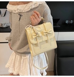 Détail du sac à dos en similicuir jaune crème avec nœuds et pendentif en perles