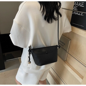 Détail du sac à bandoulière noir grainé avec breloque ronde en métal et fine lanière