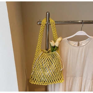 Detailed close-up of yellow hand-woven bucket bag with a white drawstring inner pouch