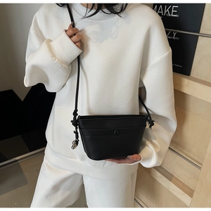 Détail du sac bandoulière en cuir grainé noir avec boucle magnétique et bandoulière fine