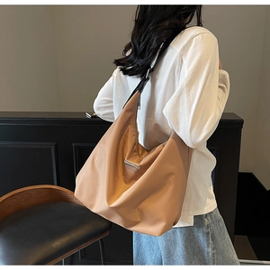 Detail view of large caramel hobo bag showing glossy nylon fabric and side zipper