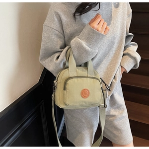 Detail einer hellgrünen Nylon-Minitasche mit Rundlogo und verstellbarem Gurt am Model