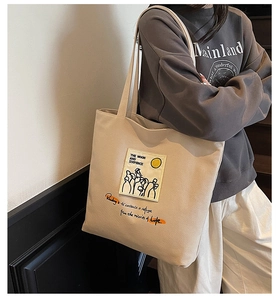 Detail of beige canvas tote bag with artistic printed patch and motivational text
