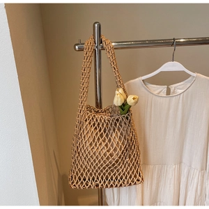Detailed view of woven hollow shoulder bag featuring a drawstring liner and mesh texture
