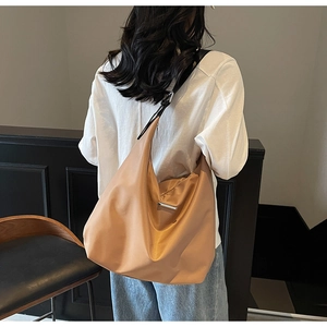 Rear view of model wearing a large khaki crossbody tote bag for commuting and travel