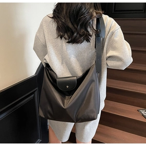 Detail of black oxford fabric tote bag featuring wide adjustable strap and metal buckle closure