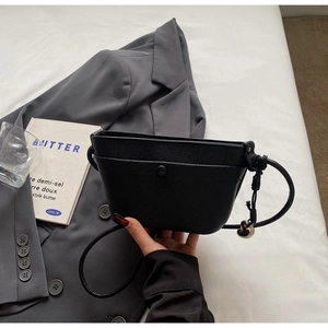 Détail d'un sac bandoulière en cuir grainé noir avec charme cœur argenté et bouton pression