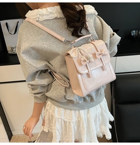 Détail d'un sac à dos rose brillant avec nœud en perles et décorations rubans