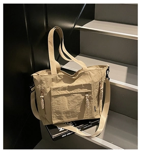 Detailed view of beige nylon tote bag with front zipper pocket and adjustable strap