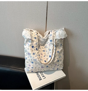 Detailed view of floral tote bag featuring elegant white lace trim and blue floral patterns