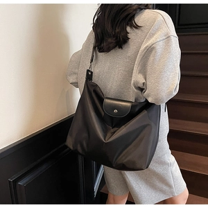 Detail view of the black nylon tote bag showing the leather flap and metal snap button