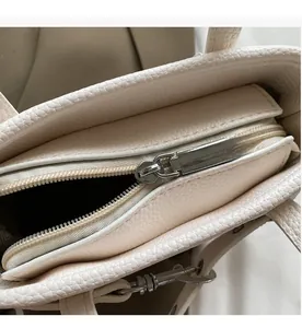Dettaglio della cerniera argentata su una borsa a secchiello in pelle beige