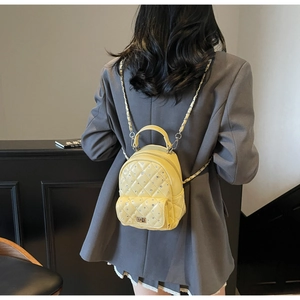 Detail of lemon yellow quilted mini backpack with rhinestone decor and chain straps